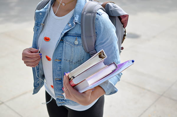 A female student carrying a backpack and books.
