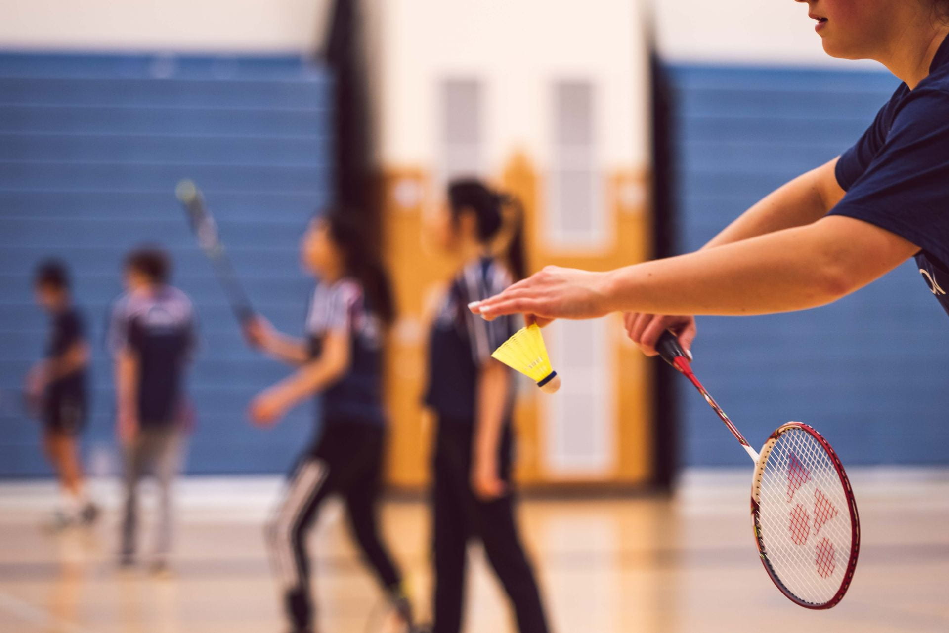 A person getting ready to serve a shuttlecock in badminton.