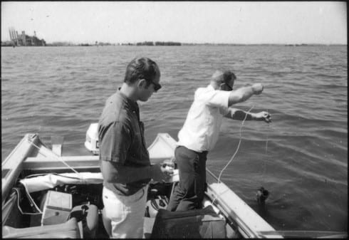 Two men in an outboard fishing boat conducting water tests