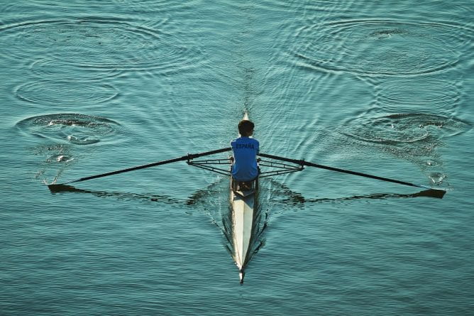 Person rowing a small boat on calm waters