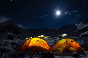 Tents illuminated from within on a dark night.